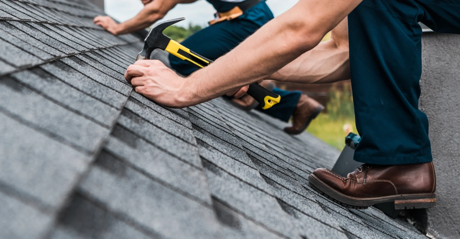 Ett team av takläggare säkrar ett papptak på ett sluttande tak medan de bär säkerhetsutrustning, i Borås, Fristad och Göteborg.