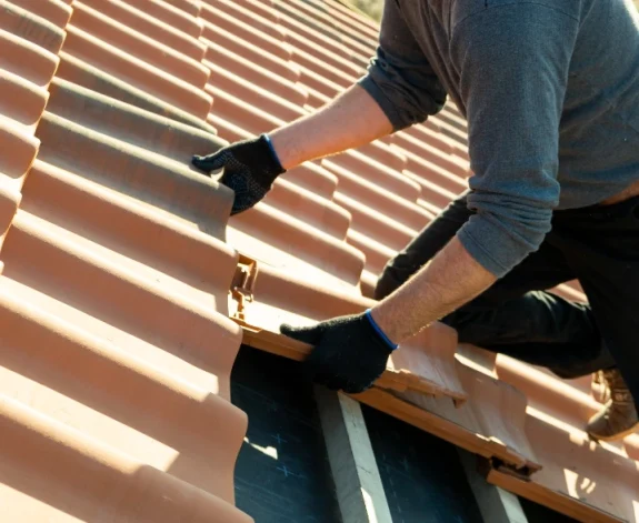En erfaren takläggare lägger tegelpannor på en villa. I Borås, Fristad och Göteborg.